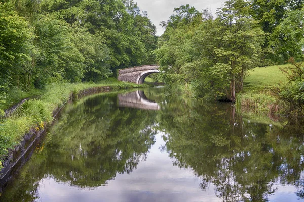 Vista de un canal británico en un entorno rural con puente de piedra —  Fotos de Stock