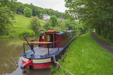 Narrowboat moored on a British canal in rural setting clipart