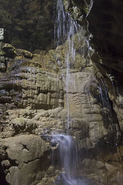 Formações rochosas geológicas e cachoeira em uma caverna subterrânea — Fotografia de Stock