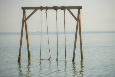Tropikal plajda sığ suda ahşap salıncak