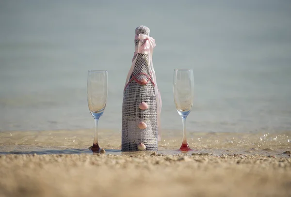 Bottle of champagne and glasses on a tropical beach — Stock Photo, Image