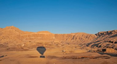 Mısır 'ın batı kıyısındaki Hatshepsut Tapınağı üzerinde uçan sıcak hava balonunun gölgesi.