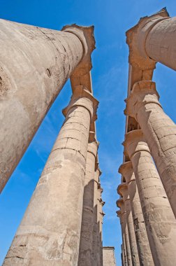 Eski Mısır Luxor tapınağındaki sütunlara mavi gökyüzü arka planına sahip hiyeroglif oymalar