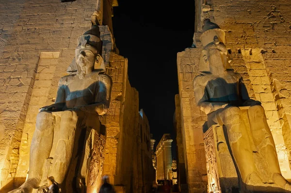 古代エジプトのルクソール神殿への入り口のパイロンにラムセス2世の大規模な彫像は夜の間にライトアップ — ストック写真