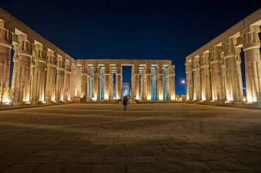 Large columns in hypostyle hall at ancient egyptian Luxor Temple lit up during night clipart