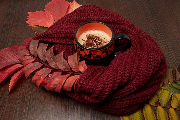 Sonbahar ruh hali, sıcaklık ve konfor sarı-kırmızı yaprakları tarafından çevrili bir atkı sarılı kahve gösteriyor ev atmosferin fotoğraf taşır