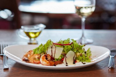 Karides, peynir, soğan, marul ve dolmalık biber salatası. Beyaz şarap ve zeytinyağı. Her şey tablo restoranda servis edilir. Portre.