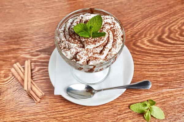 kremalı tatlı çikolata parçaları ile ince dal nane ile dekore edilmiş, peçete ve bir kaşık ile bir daire üzerinde duran, tarçın ve nane, yanındaki yakın üstten görünüm, düz yatıyordu