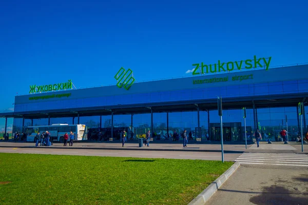 MINSK, BÉLARO - 01 DE MAYO DE 2018: Personas no identificadas caminando para utilizar el cruce peatonal del aeropuerto internacional de Zhukovsky, edificio de aviación en un hermoso cielo azul en el soleado en Minsk — Foto de Stock