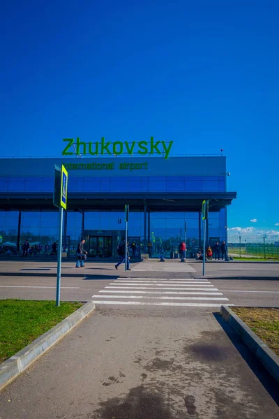 MINSK, BÉLARO - 01 DE MAYO DE 2018: Personas no identificadas caminando para utilizar el cruce peatonal del aeropuerto internacional de Zhukovsky, edificio de aviación en un hermoso cielo azul en el soleado en Minsk — Foto de Stock