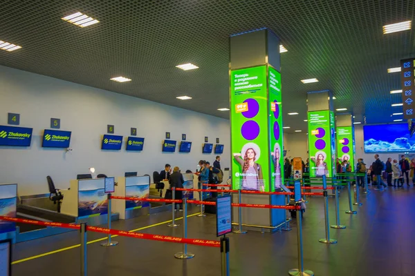 MINSK, BÉLARO - 01 DE MAYO DE 2018: Vista interior de personas no identificadas esperando en la fila de check-in, dentro del aeropuerto de Minsk rodeada de coloridos signos y turistas de diferentes países —  Fotos de Stock