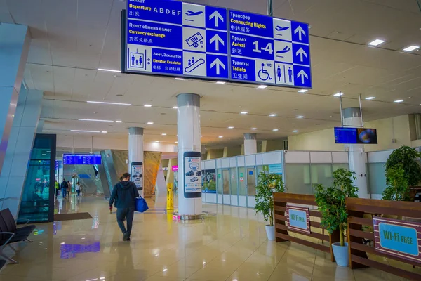 MINSK, BÉLARO - 01 DE MAYO DE 2018: Vista interior de personas no identificadas caminando bajo un letrero informativo dentro del aeropuerto internacional de Minsk — Foto de Stock