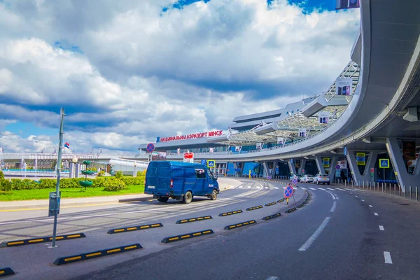 MINSK, BELARUS - 01 DE MAYO DE 2018: Vista al aire libre de los coches estacionados en la entrada del edificio del aeropuerto de Minsk en un día nublado con algunas plantas en un pequeño jardín en frente — Foto de Stock