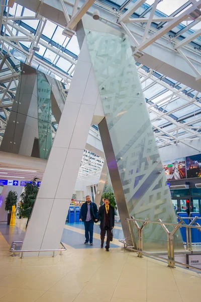 MINSK, BELARUS - 01 MAI 2018 : Vue intérieure d'un homme d'affaires marchant avec leurs lugagges et traversant sous un énorme colum métallique, à l'intérieur de l'aéroport de Minsk entourant de panneaux colorés — Photo