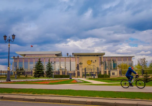 MINSK, BELARUS - 01 DE MAYO DE 2018: Hombre montando una bicicleta frente al Palacio de la Independencia, residencia del Presidente de la República Bielorrusia, edificio utilizado para las funciones oficiales del Estado en la capital — Foto de Stock