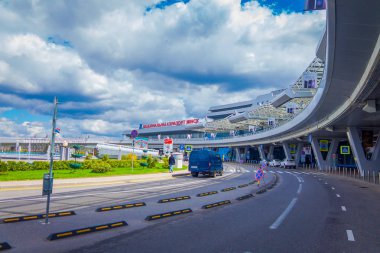Minsk, Beyaz Rusya - 01 Mayıs 2018: Minsk Havaalanı bulutlu bir günde küçük bir bahçe önünde bazı bitkilerde bina girin, park etmiş arabaların açık görünüm