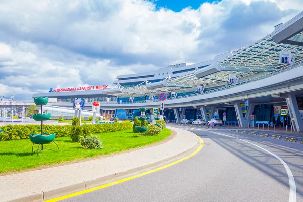 MINSK, BELARUS - 01 MAI 2018 : Vue extérieure des voitures garées à l'entrée du bâtiment de l'aéroport de Minsk par une journée nuageuse avec quelques plantes dans un petit jardin en face — Photo