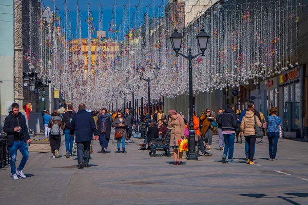 Moskova, Rusya - Nisan, 24, 2018: açık görünüm kimliği belirsiz kişi şenlikli bir Noel ışıkları altında Nikolskaya sokaklarda güneşli bir günde yürüyüş