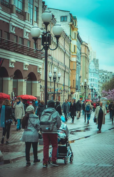 MOSCÚ, RUSIA - 24 DE ABRIL DE 2018: Personas no identificadas llevando ropa de abrigo y caminando por las calles decoradas para la celebración de la Pascua con un árbol rosa y algunas lámparas públicas —  Fotos de Stock