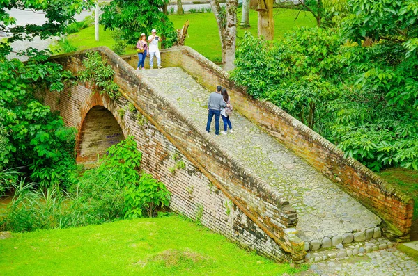 Popayan, Kolumbia - 06 lutego 2018: Niezidentyfikowanych osób chodzenia i robienia zdjęć mostu murowany położony w środku lasu w kolonialne miasto Popayan — Zdjęcie stockowe