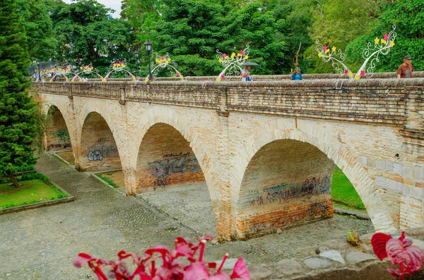 POPAYAN, COLOMBIA - 06 DE FEBRERO DE 2018: Personas no identificadas caminando en el puente de Humilladero a través de un colorido arco en la ciudad colonial Popayan — Foto de Stock