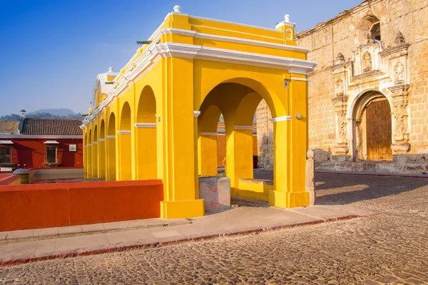 Ciudad de Guatemala, Guatemala, 25 de abril de 2018: Vista al aire libre de muchas columnas en una estructura de edificio amarillo ubicada en el centro de la ciudad, cerca de edificios antiguos en la ciudad de Antigua — Foto de Stock