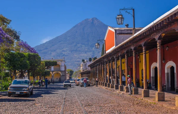 Ciudad de Guatemala, Guatemala, 25 aprile 2018: Strada a partecipazione lapidata e persone che camminano e si godono la splendida giornata di sole della città di Antigua e del vulcano Agua sullo sfondo Guatemala — Foto Stock