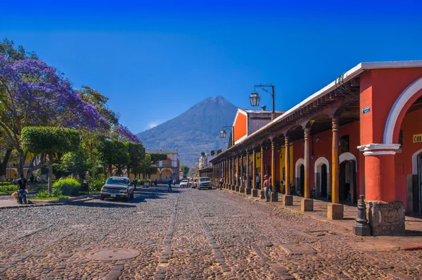 Ciudad de Guatemala, Guatemala, 25 de abril de 2018: Stoned apvement street and people walking and enjoying the gorgeous sunny day of Antigua city and the Agua volcano in the background Guatemala — Foto de Stock