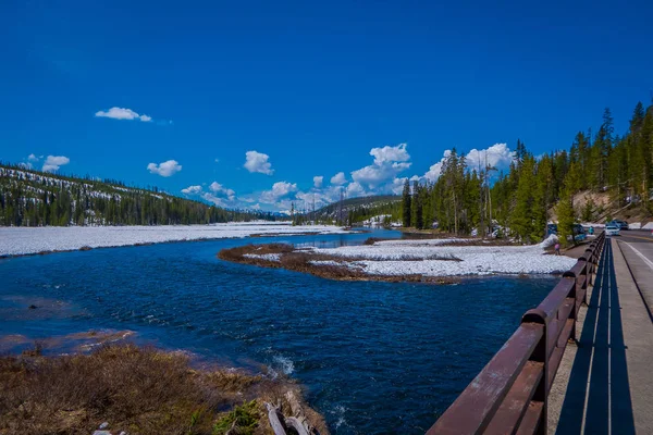Vista al aire libre del río congelado parcial en el Parque Nacional de Yellowstone, foto tomada desde un puente en el parque, en un hermoso día soleado con cielo azul — Foto de Stock