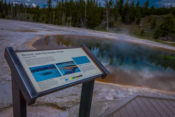 YELLOWSTONE, MONTANA, USA 24 DE MAYO DE 2018: Signo informativo de piscinas cromáticas en aguas termales y estera microbiana naranja en la antigua cuenca de géiseres del Parque Nacional Yellowstone, Wyoming — Foto de Stock