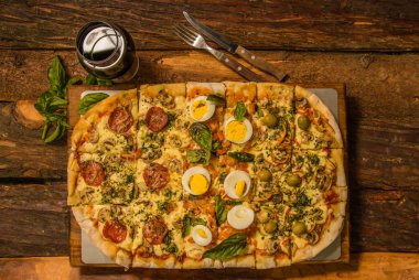 Ahşap bir masa, sabah kahvaltı lezzetli pizza biberli, mozzarella, domates sos ve haşlanmış yumurta parçaları ile aboive görünüm