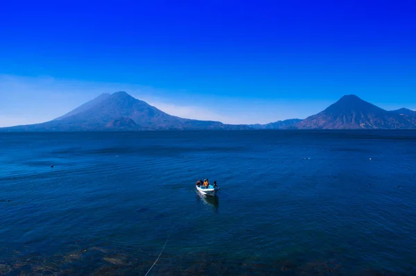 Bela vista ao ar livre de pequenos barcos no Lago Atitlan é o lago mais profundo de toda a América Central, com uma profundidade máxima de cerca de 340 metros, com vulcão em fundo na Guatemala — Fotografia de Stock