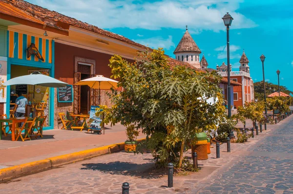 GRANADA, NICARAGUA - 28 APRILE 2016: Veduta esterna di ristoranti in una coloniale e bellissimi edifici colorati in fila in città con alcune sedie a sdraio per il turista da mangiare — Foto Stock