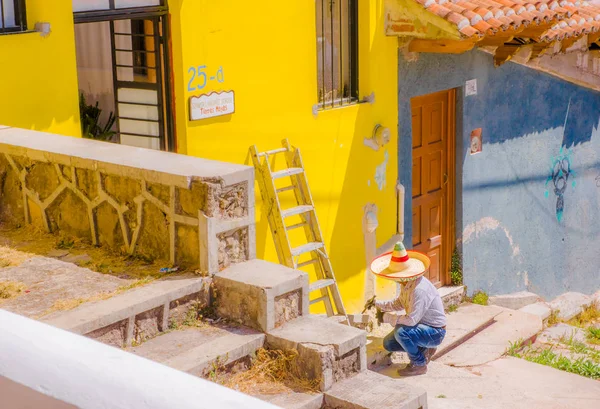SAN CRISTOBAL DE LAS CASAS, MEXICO, MAY, 17, 2018: Unidentified man using a mexican hat to protect from the heavy sun and painting the wall with yellow color in san Cristobal de las Casas — Stock Photo, Image