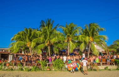 San Juan del Sur, Nikaragua - 11 Mayıs 2018: iç çamaşırı ve temiz giysiler giyiyor açık partide San Juan del Sur bazı palmiye ağaçları altında güneşli bir insan kalabalığı