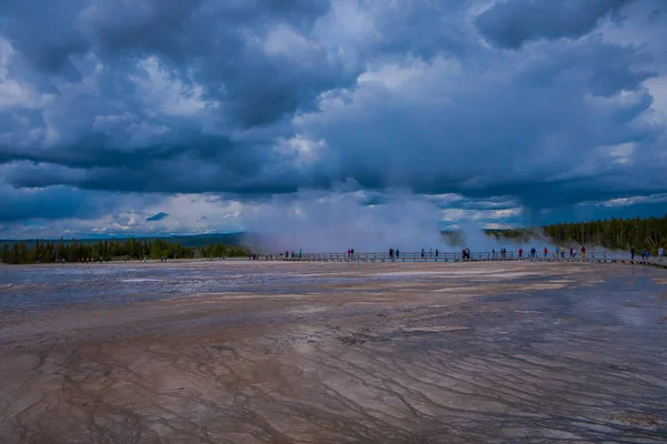 Vista al aire libre de los turistas caminando en un paseo marítimo en el horizonte, alrededor de la Gran Primavera Prismática en el Parque Nacional de Yellowstone, este géiser es uno de los más activos — Foto de Stock