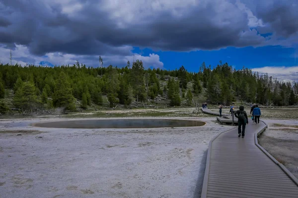 Йеллоустон, Монтана, США 24 мая 2018 года: Неопознанные туристы прогуливаются по старому верному гейзеру в Йеллоустонском национальном парке по набережной, окруженной паром — стоковое фото