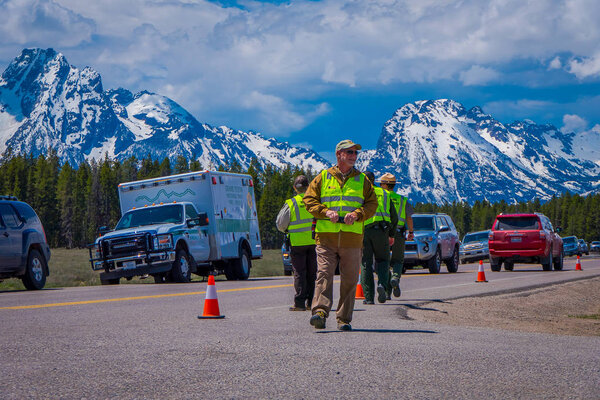 YELLOWSTONE, MONTANA, USA MAY 24, 2018: Outdoor view of cars parked at one side of the road with crowd of people at Yellowstone Grand Teton National Park, Wyoming