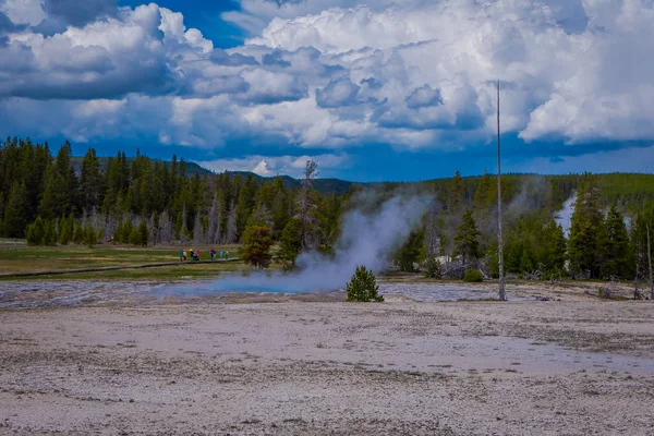 YELLOWSTONE, MONTANA, USA 24 DE MAYO DE 2018: Turistas no identificados caminando alrededor del viejo géiser fiel en el Parque Nacional Yellowstone en un paseo marítimo rodeado de vapor — Foto de Stock