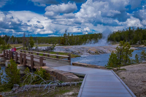 YELLOWSTONE, MONTANA, USA 24 DE MAYO DE 2018: Turistas no identificados caminando en el puente de madera sobre el río de la hoguera en el Parque Nacional Yellowstone — Foto de Stock