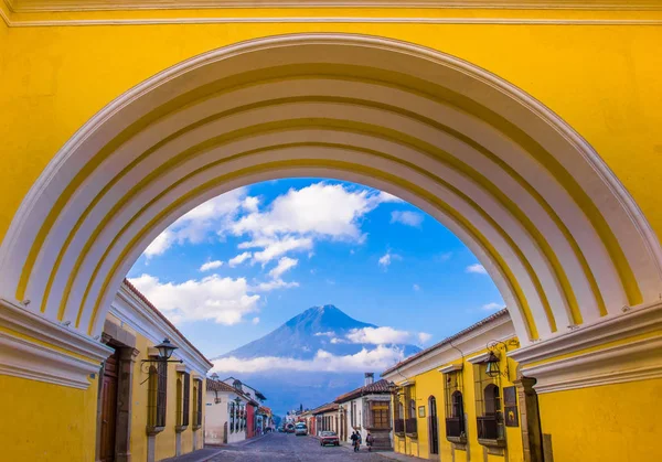 Ciudad de Guatemala, Guatemala, 25 de abril de 2018: Vista do vulcão ativo Água no fundo através de um arco amarelo colorido da cidade de Antigua, na Guatemala — Fotografia de Stock