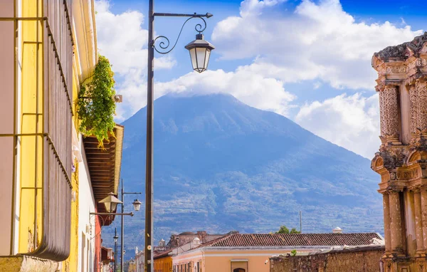 Vista ao ar livre da varanda com algumas plantas em um pote e luzes de lâmpada publibc com um vulcão atrás, parcial coberto com nuvens em um lindo dia ensolarado em Antigua Guatemala — Fotografia de Stock