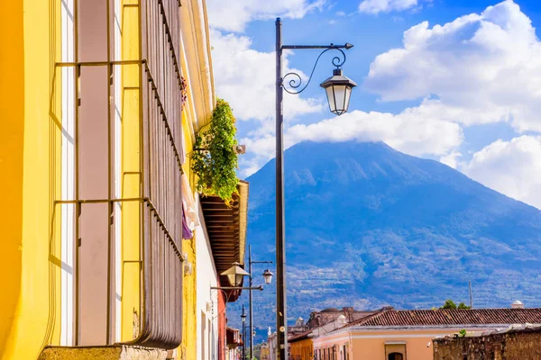 Vista ao ar livre da varanda com algumas plantas em um pote e luzes de lâmpada publibc com um vulcão atrás, parcial coberto com nuvens em um lindo dia ensolarado em Antigua Guatemala — Fotografia de Stock