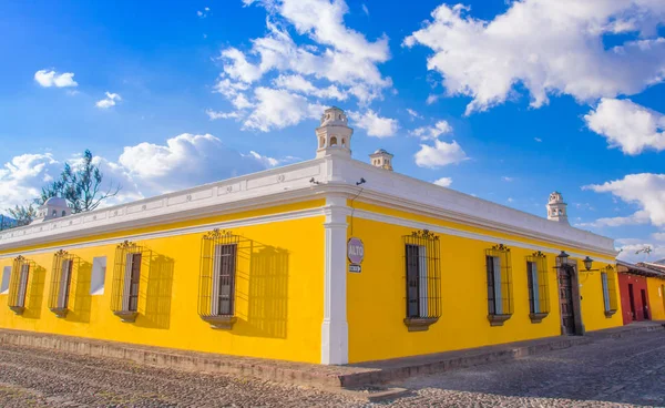 Ciudad de Guatemala, Guatemala, 25 de abril de 2018: Vista al aire libre de la perspectiva de esquina de una casa colonial de color amarillo brillante con ventanas con rejas en la ciudad de Antigua — Foto de Stock