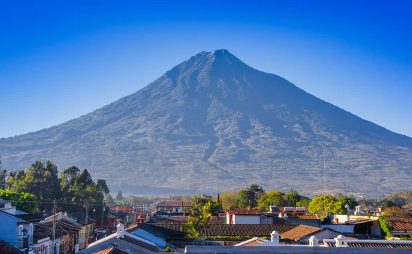 在安提瓜市一个美丽的晴天和蓝天上, 在安提瓜的老处所屋顶上的火山。 — 图库照片