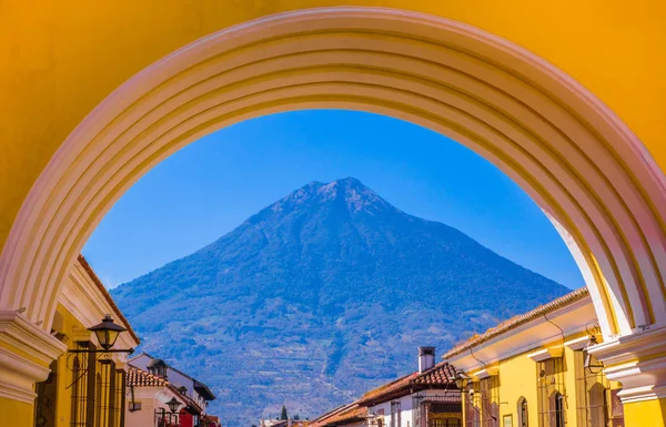 Ciudad de Guatemala, Guatemala, April, 25, 2018: uitzicht op de vulkaan Agua in de achtergrond door een kleurrijke gele boog van Antigua stad in Guatemala — Stockfoto