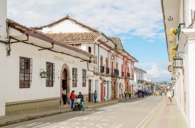 POPAYAN, COLOMBIA - MARCH 31, 2018: Outdoor view of people walking in the streets, white colonial buildings in the city of Popayan during gorgeous sunny day clipart