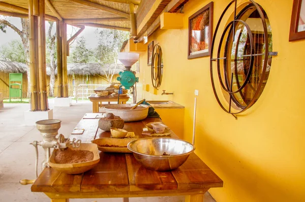 Nahaufnahme von Kakaobohnen und Kakao, gemahlen über einem Holztisch, mit Handmühle, vor verschwommenem Hintergrund — Stockfoto