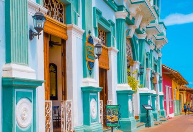GRANADA, NICARAGUA, MAY, 14, 2018: Outdoor view of facade buildings with turquoise wall and wooden door in the historic city center of Granada in Spanish colonial style architecture clipart