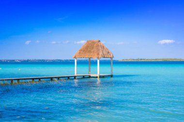Color graded picture of a pier with clouds and blue water at the Laguna Bacalar, Chetumal, Quintana Roo, Mexico clipart